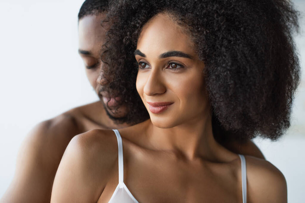 Smiling african american woman in bra standing near blurred shirtless boyfriend  - Foto, afbeelding