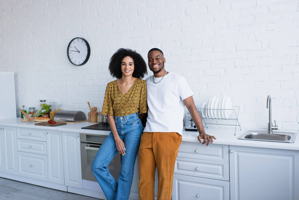 alegre africano americano pareja mirando cámara en cocina  - Foto, imagen