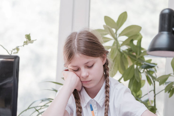 Schoolgirl self isolation using laptop for his homework. Gaming, education and school concept - sad girl with laptop and at home. Girl having hard time doing homework online, sitting depressed indoors - Zdjęcie, obraz