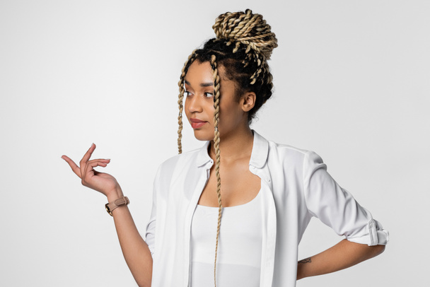young african american businesswoman with dreadlocks looking away and pointing with finger isolated on white - Foto, imagen