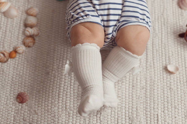 Μικρά πόδια. Κοριτσάκι με άσπρες κάλτσες και φόρμα. Άποψη από ψηλά - Φωτογραφία, εικόνα
