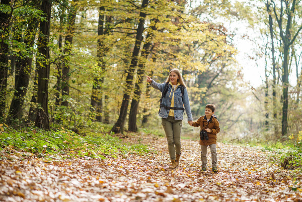Onnellinen äiti ja poika vaeltavat metsässä. - Valokuva, kuva