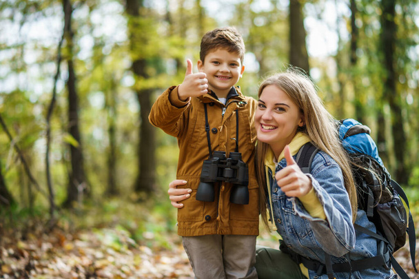 幸せな母親と息子は秋に森の中をハイキングしています. - 写真・画像
