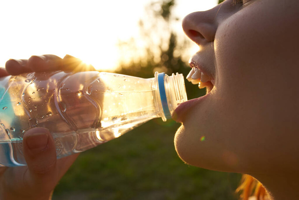 fröhliche Frau trinkt Wasser aus einer Flasche  - Foto, Bild