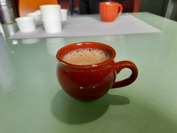 Nahaufnahme von einzelnen roten oder braunen Ton, Sand Kaffeetasse auf einem Tisch - Foto, Bild