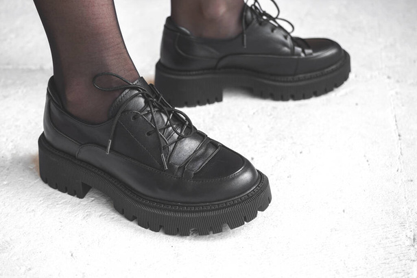 Mode schwarze Stiefel auf weiblichen Beinen. Modell im Atelier mit Betonhintergrund, urban casual design concept photo - Foto, Bild