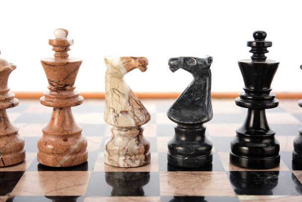 šachové figurky jako soupeři, uprostřed na béžové a černé korálové mramorové šachovnici. Závěrečná hra koncept soutěž, Classic turnaj. - Fotografie, Obrázek