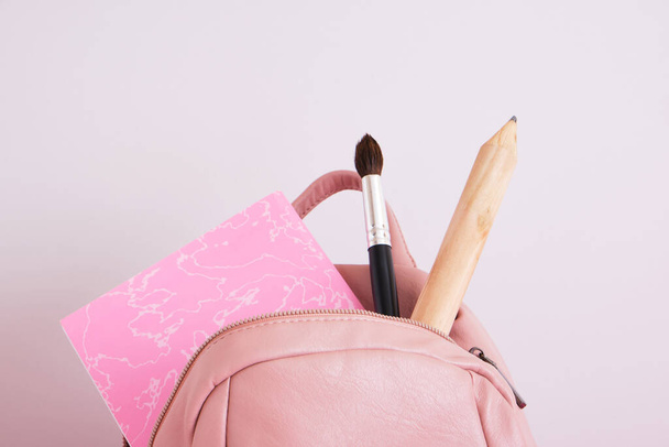 bőr rózsaszín váll hátizsák szürke háttér, iskola hölgyek hátizsák nagy bálna, nagy ceruza és notebook, vissza az iskolába koncepció - Fotó, kép