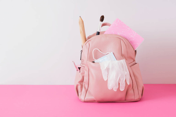 leather pink backpack on the shoulders on a gray background, school ladies backpack with a big whale, a large pencil and a notebook, back to school concept, face mask and gloves, lockdown at school - Fotografie, Obrázek
