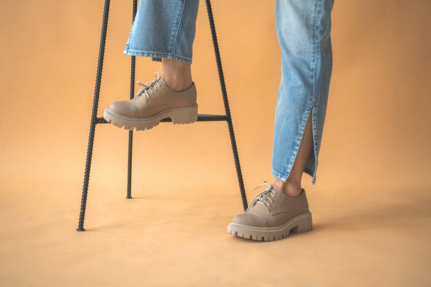 Nastolatka w luźnych trampkach. Modne buty na damskich stopach w dżinsowych ciuchach. Styl życia i modne tło projektowe  - Zdjęcie, obraz