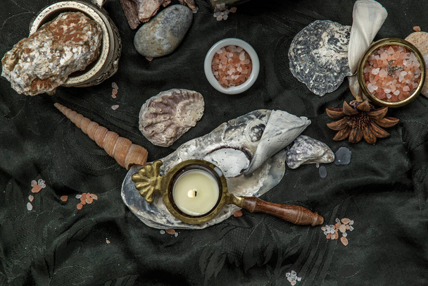 Beauty composition with Burning candle aroma oil lamp and Dry flower petals and Pine cones, Natural pine wood disc, Stones and Shells, Himalayan salt on dark background. Aromatherapy concept. - Фото, зображення