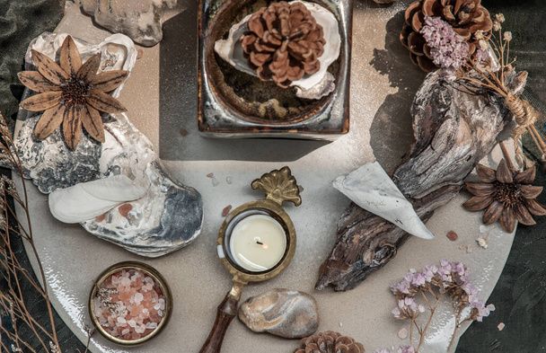 Beauty composition with Burning candle aroma oil lamp and Dry flower petals and Pine cones, Natural pine wood disc, Stones and Shells, Himalayan salt on dark background. Aromatherapy concept. - Fotografie, Obrázek