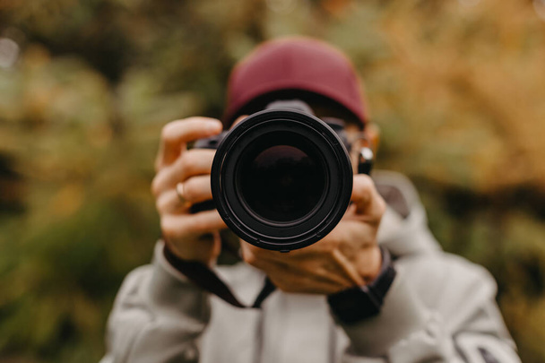 fotógrafo barbudo elegante com uma câmera em suas mãos tira uma foto no parque de outono - Foto, Imagem