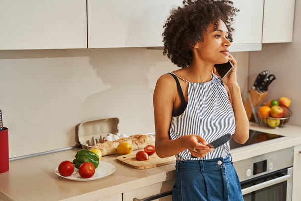 Söpö naiskokki, jolla on puhelinkeskustelu keittiössä - Valokuva, kuva