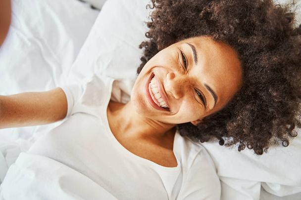 Korkea-henkinen hymyilevä tummahiuksinen nainen ottaa selfien - Valokuva, kuva