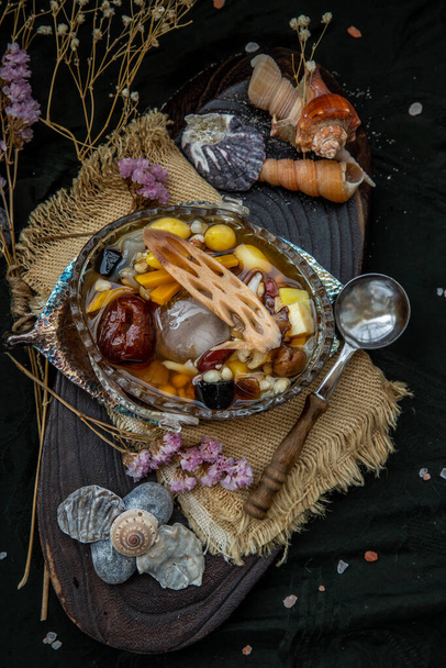 Sweet dessert : kind of Chinese dessert with boil sugar syrup is delicious here are many grains, including green beans, lotus seeds, millet, persimmon, jelly, longan, boiled flour and sugar add more cool feeling with ice. Selective focus. - Foto, Imagen