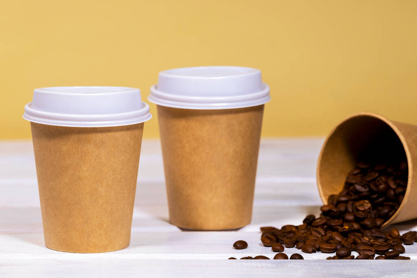 Coffee to go in Papier-Eco-Tasse mit hölzernem und hellorangefarbenem Hintergrund, Fast Food, Copyspace, Koffein-Drink zum mitnehmen - Foto, Bild