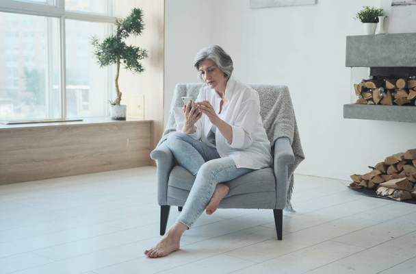 Розслаблена зріла стара жінка використовує додатки для мобільних телефонів
 - Фото, зображення