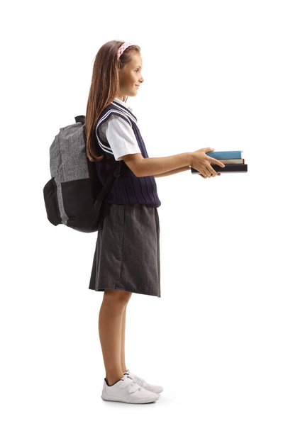 Full length profile shot of a schoolgirl giving books and smiling isolated on white background - 写真・画像