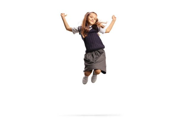 Happy schoolgirl in a uniform jumping isolated on white background - Фото, изображение