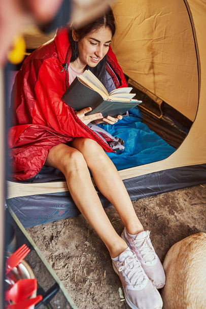 Счастливая молодая женщина наслаждается чтением в палатке - Фото, изображение