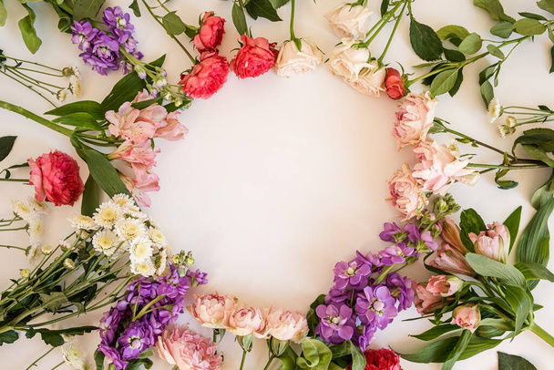 Abstract floral aesthetic background. Round floral frame wreath of colourful roses, peony flowers on white background with blank copy space mockup. Beautiful flowers and petals template - Photo, Image