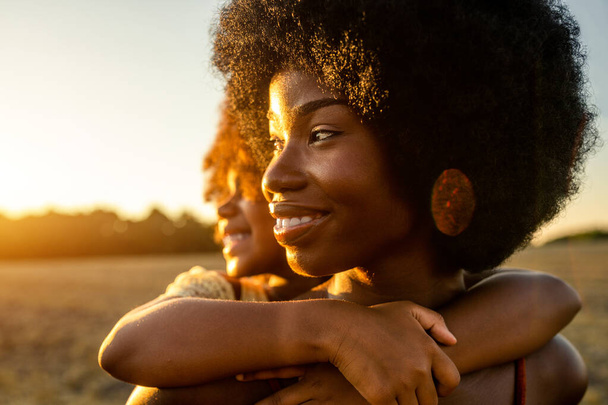 Beautiful afro-american mom and daughter palying and having fun in a sunflowers field - Foto, afbeelding