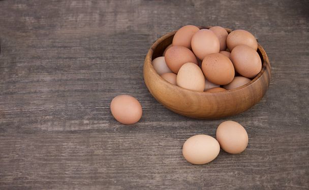 Schaal van rauwe verse bruine biologische eieren op houten ondergrond. - Foto, afbeelding