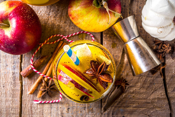Boozy Pumpkin Party Punch, thanksgiving sangria with pumpkin juice, apple, pear and spices, cozy wooden background with warm sweater and ingredients copy space - Фото, изображение