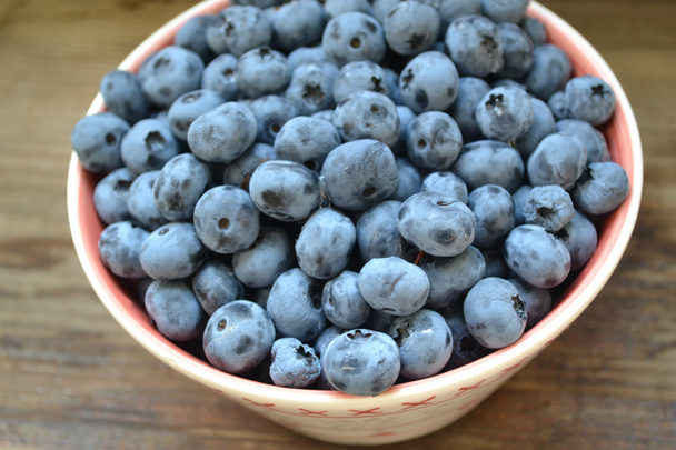 Healthy and delicious blueberries in a bowl on a wooden table - Photo, Image