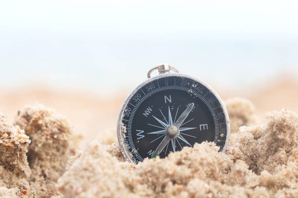 Classic navigation compass on beach against blue sea as symbol of tourism with compass, travel with compass and outdoor activities with compass - Valokuva, kuva