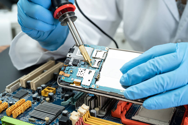E-déchets, technicien de réparation à l'intérieur du disque dur par le fer à souder. Circuit intégré. le concept de données, matériel, technicien et technologie. - Photo, image