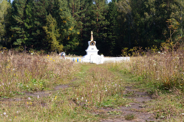 Sommerlandschaft aus weißem buddhistischen Stupa Aufklärung gegen dunklen Wald in der Nähe von Krasnojarsk, Russland - Foto, Bild