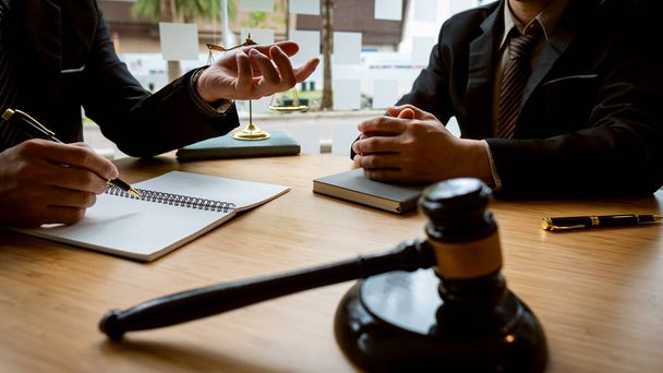 A male lawyer consults a team of legal clients and businessmen who are negotiating contracts. Human hands work with papers at the desk and sign contracts.Keywords: on the table with hammer and scales - Fotó, kép