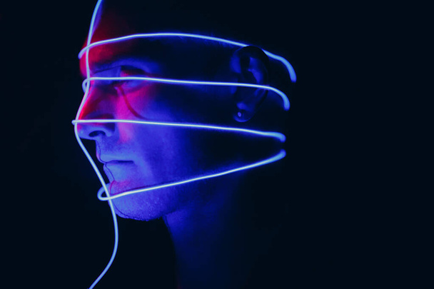 Portrait of man with neon glow lines on his face. Concept cyberpunk and virtual reality. - Foto, afbeelding