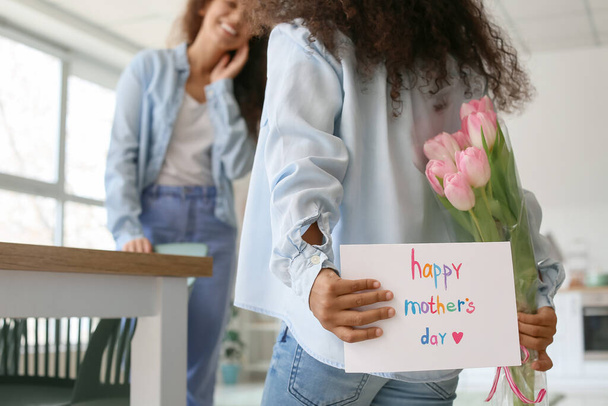 Menina afro-americana com cartão de saudação e flores para sua mãe em casa - Foto, Imagem