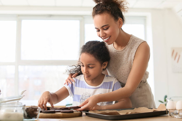 アフリカ系アメリカ人の女の子と彼女の母親調理中クッキー - 写真・画像