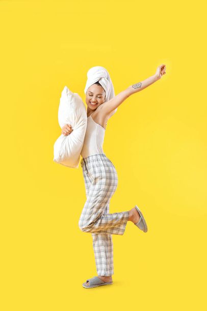 Beautiful young woman with pillow on color background - Фото, изображение
