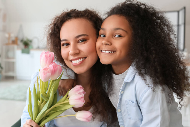 Petite fille afro-américaine et sa mère avec des fleurs à la maison - Photo, image