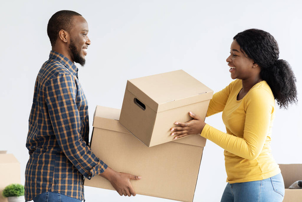 Boldog fekete házastársak költözik az új apartman, hordozó tartozékok kartondobozokban - Fotó, kép