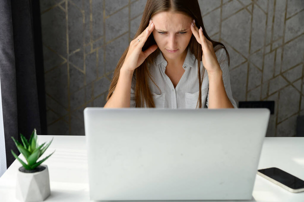 Depressed young businesswoman holding head in hands, has problem - Photo, image