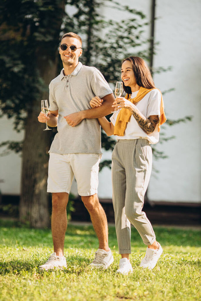 Full-length portrait of young smiling couple walking in garden on warm summer day - Photo, Image