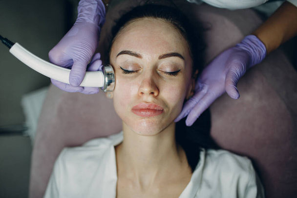 Close up da cabeça mulher recebendo eletroporação fonoforese terapia facial no salão de beleza spa. - Foto, Imagem