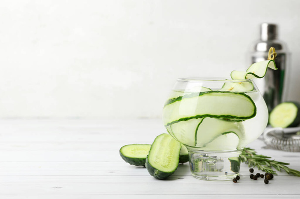 Glass of cold gin tonic and cucumber slices on light wooden background - Fotoğraf, Görsel