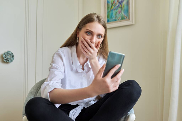 Emotional young beautiful woman looking at smartphone screen - Foto, immagini