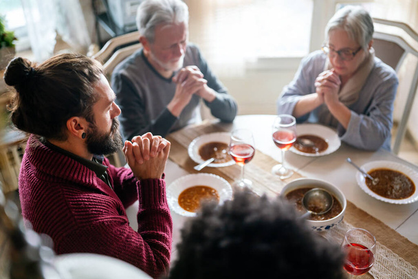 Happy multiethnic family praying before meal at home. People religion concept - Foto, Imagen