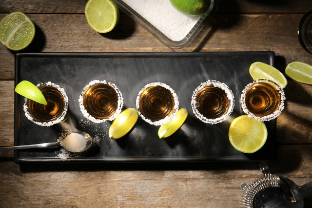 Tomas de tequila sabroso con lima sobre fondo de madera - Foto, Imagen