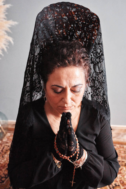 Μια γυναίκα με ψηλή χτένα και μαύρο πέπλο προσεύχεται - Φωτογραφία, εικόνα