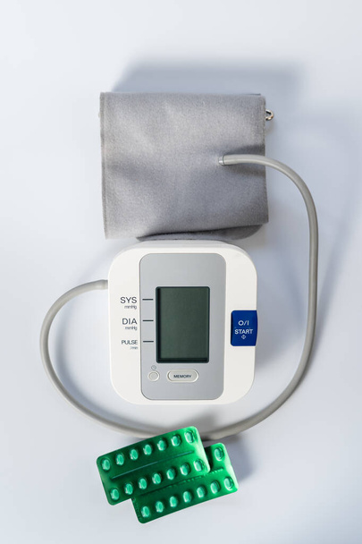 Tabletten zur Senkung des Blutdrucks und eine Maschine zur Blutdruckmessung. - Foto, Bild