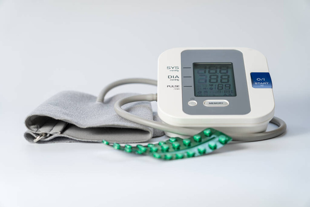 Monitor ciśnienia krwi do podjęcia ciśnienia krwi i pigułki, aby go obniżyć. - Zdjęcie, obraz